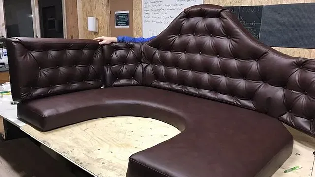 Brun, buet hjørnesofa med knappet rygg og skinntrukne flater på verkstedbord