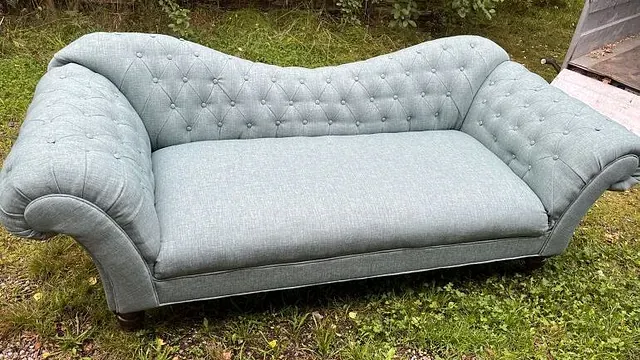 Mintgrønn sofa med buede armlener og knappet rygg, plassert ute på plen